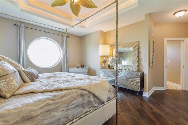 bedroom with a tray ceiling, visible vents, wood-type flooring, crown molding, and baseboards