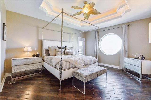 bedroom with baseboards, a ceiling fan, a tray ceiling, and dark wood-style flooring