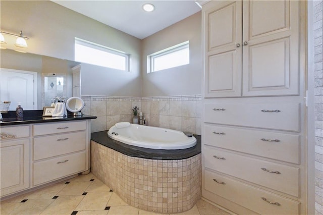 bathroom featuring a garden tub, vanity, and tile patterned flooring