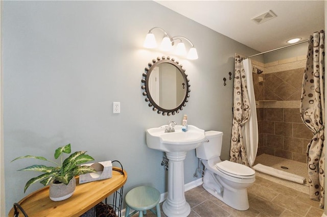 bathroom with toilet, tile patterned floors, baseboards, visible vents, and tiled shower