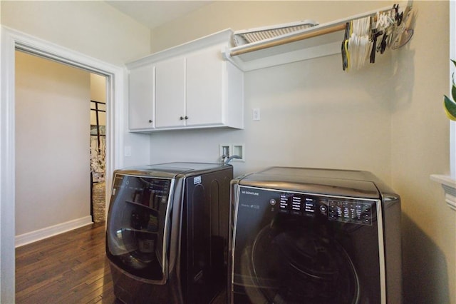 laundry room featuring cabinet space, baseboards, dark wood-type flooring, and washer and clothes dryer