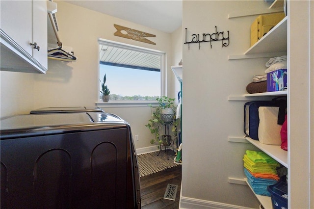 laundry room with wood finished floors, baseboards, washer and clothes dryer, and cabinet space
