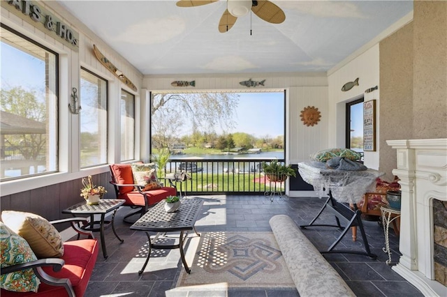 sunroom / solarium with ceiling fan and a water view