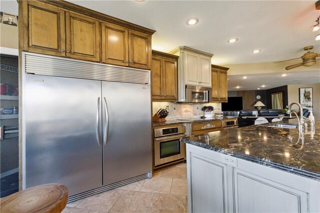 113 Lighthouse Pt, Gallatin, MO 64640 - kitchen featuring dark stone countertops, a sink, decorative backsplash, appliances with stainless steel finishes, and open floor plan