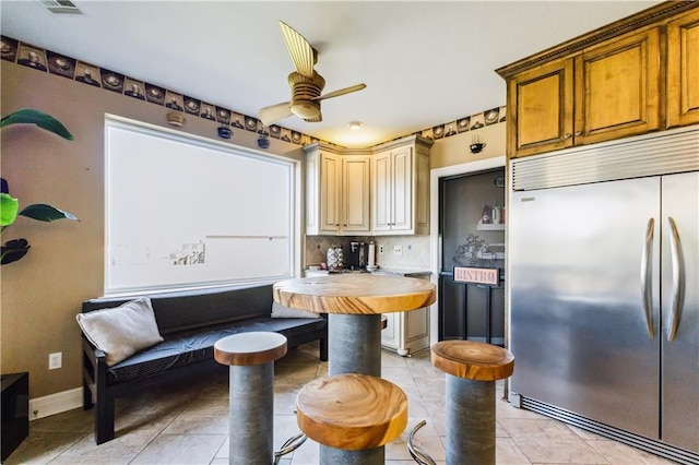 kitchen featuring a ceiling fan, light tile patterned floors, baseboards, backsplash, and stainless steel built in refrigerator