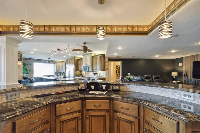 kitchen featuring open floor plan, pendant lighting, brown cabinetry, and appliances with stainless steel finishes