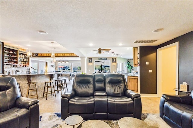 living room with a ceiling fan, a textured ceiling, visible vents, and recessed lighting