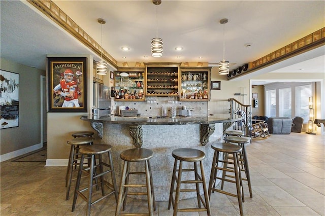 bar with wet bar, freestanding refrigerator, pendant lighting, baseboards, and decorative backsplash