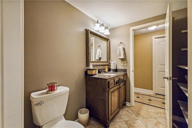 bathroom featuring tile patterned floors, a textured ceiling, toilet, baseboards, and vanity