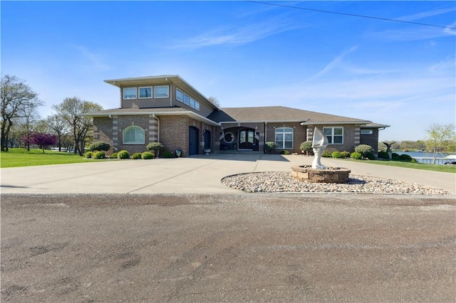 prairie-style home with brick siding, an attached garage, and curved driveway