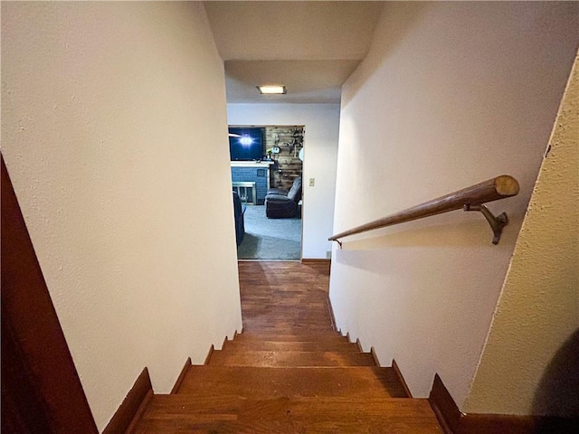 1124 Pacific Ave, Osawatomie, KS 66064 - stairs featuring a fireplace, wood finished floors, and a textured wall