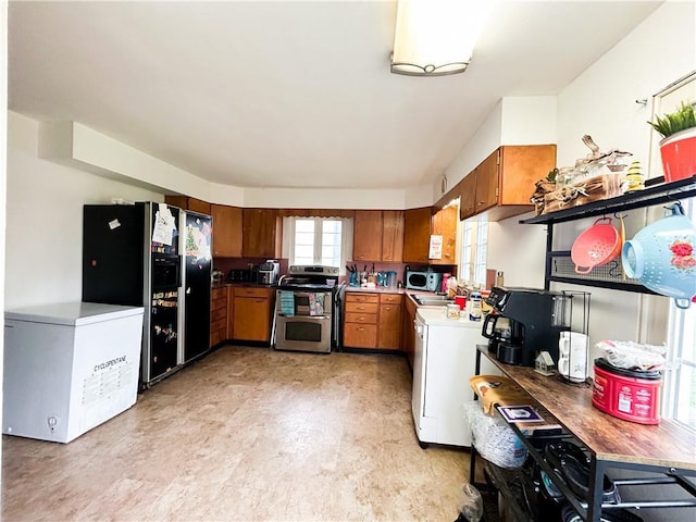 1124 Pacific Ave, Osawatomie, KS 66064 - kitchen featuring double oven range, fridge, brown cabinets, black fridge, and light countertops