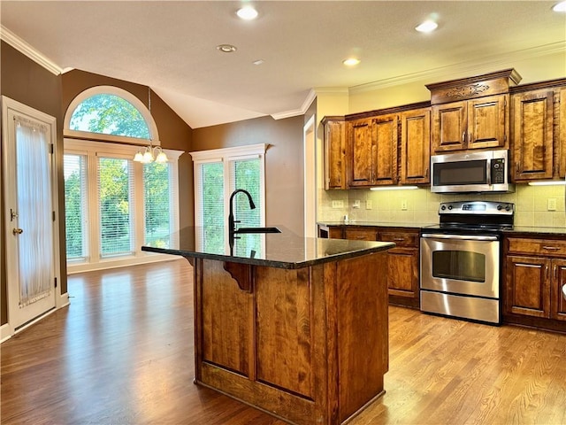 14413 Stearns St, Overland Park, KS 66211 - kitchen featuring appliances with stainless steel finishes, a sink, light wood-style floors, ornamental molding, and a center island with sink