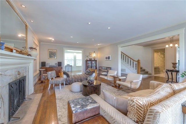 living room featuring stairs, ornamental molding, wood finished floors, and a fireplace