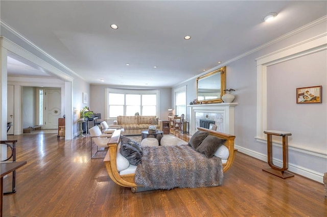 living area with ornamental molding, wood finished floors, a fireplace, baseboards, and recessed lighting