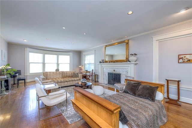 living area featuring crown molding, wood finished floors, and a high end fireplace