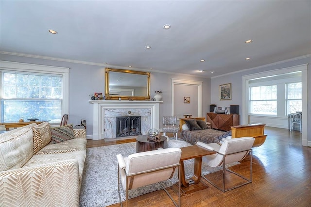 living area featuring a premium fireplace, recessed lighting, ornamental molding, and wood finished floors