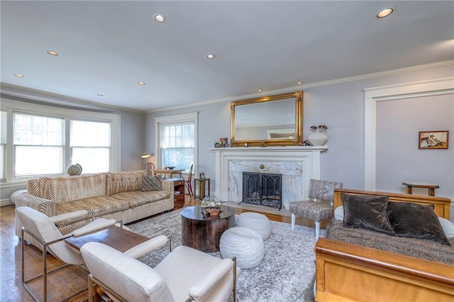 living room featuring crown molding, recessed lighting, wood finished floors, and a premium fireplace