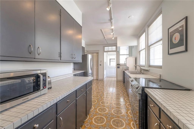 kitchen featuring a sink, appliances with stainless steel finishes, tile countertops, and track lighting