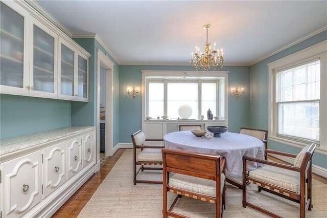 dining space featuring crown molding, baseboards, wood finished floors, and a chandelier