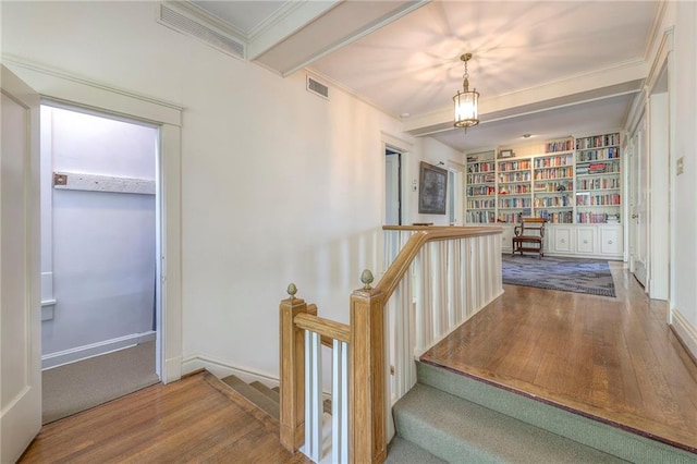 stairway with crown molding, wood finished floors, and visible vents