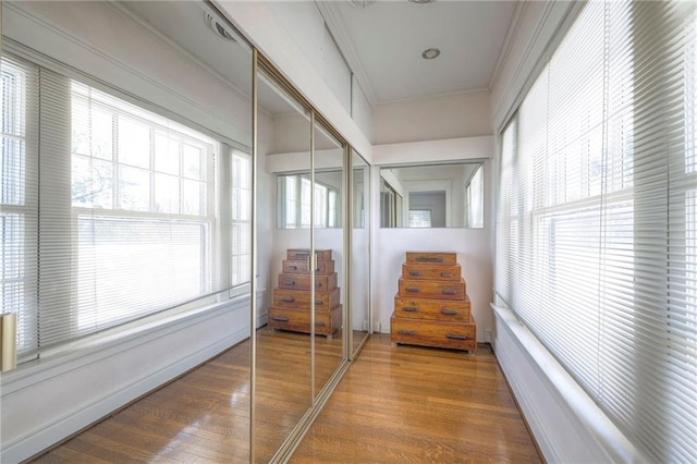 hall with ornamental molding and wood finished floors