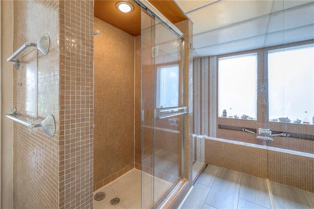full bath featuring tile patterned flooring and a shower stall