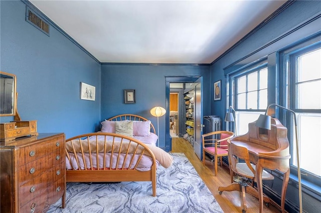 bedroom featuring crown molding, wood finished floors, and visible vents