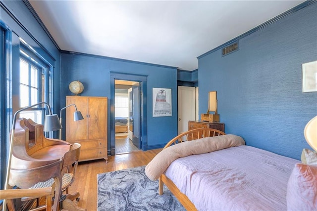 bedroom with baseboards, an accent wall, and wood finished floors