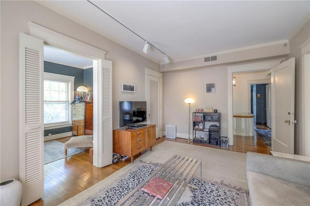 living room featuring crown molding, track lighting, light wood finished floors, baseboards, and visible vents