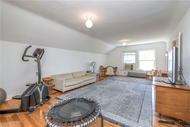 living area with radiator, baseboards, wood finished floors, and lofted ceiling