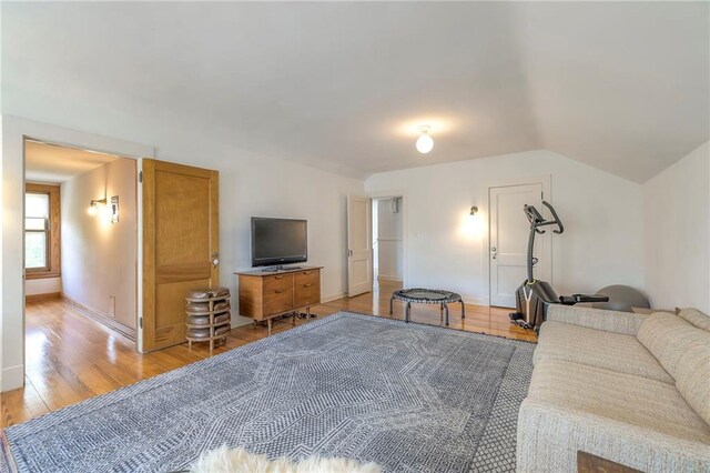 living room with light wood-style floors, baseboards, and vaulted ceiling