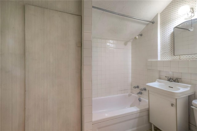 full bath with tile walls, vanity, toilet, lofted ceiling, and bathing tub / shower combination