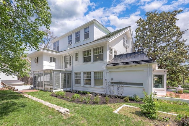 back of property with a sunroom, a lawn, and stucco siding