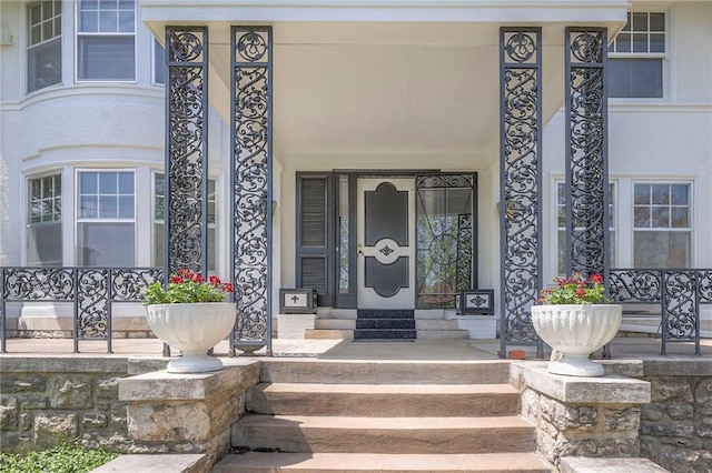 view of exterior entry featuring a porch and stucco siding