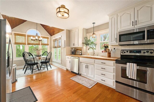 17014 NE 119th St, Kearney, MO 64060 - kitchen with stainless steel appliances, a sink, light wood-style floors, hanging light fixtures, and lofted ceiling