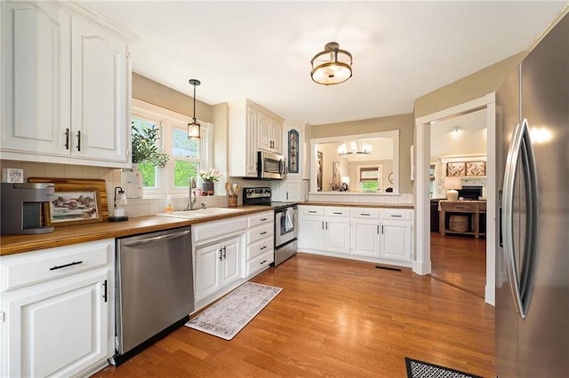 17014 NE 119th St, Kearney, MO 64060 - kitchen featuring stainless steel appliances, a sink, light wood-style floors, a chandelier, and white cabinetry