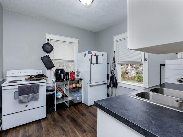 3931 Norledge Ave, Kansas City, MO 64123 - kitchen with dark wood-style flooring, a textured ceiling, white cabinets, white appliances, and dark countertops