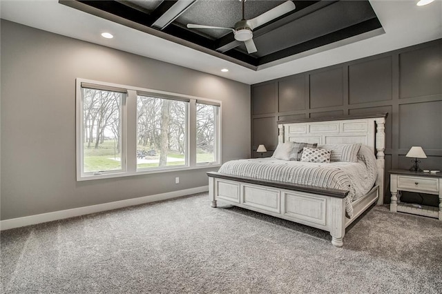 bedroom featuring a raised ceiling, baseboards, a decorative wall, light colored carpet, and recessed lighting