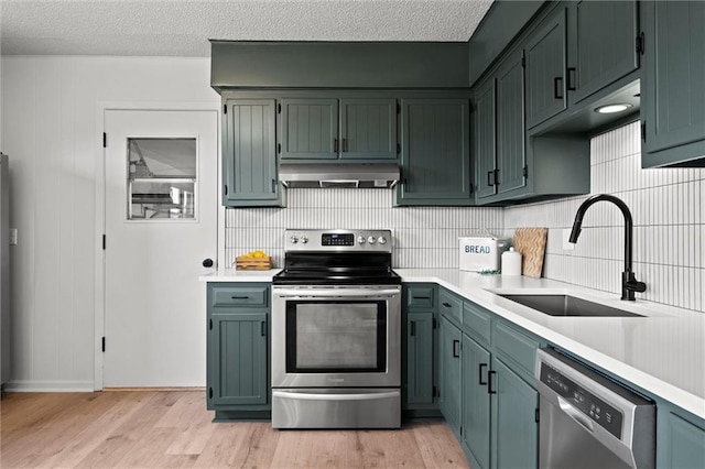 14875 Edgerton Rd, Gardner, KS 66030 - kitchen with appliances with stainless steel finishes, under cabinet range hood, light countertops, decorative backsplash, and light wood-style floors