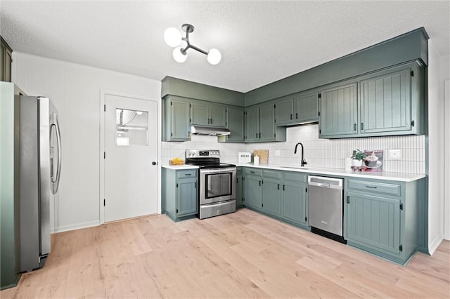 14875 Edgerton Rd, Gardner, KS 66030 - kitchen featuring stainless steel appliances, under cabinet range hood, light wood-style flooring, light countertops, and a textured ceiling