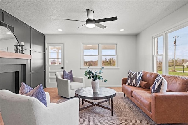 14875 Edgerton Rd, Gardner, KS 66030 - living area with light wood-type flooring, ceiling fan, a textured ceiling, a fireplace, and recessed lighting