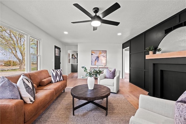 14875 Edgerton Rd, Gardner, KS 66030 - living room featuring light wood finished floors, a fireplace, ceiling fan, a textured ceiling, and recessed lighting