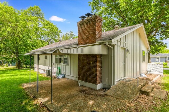 7201 E 130th Ter, Grandview, MO 64030 - rear view of house with board and batten siding, roof with shingles, a chimney, and a yard