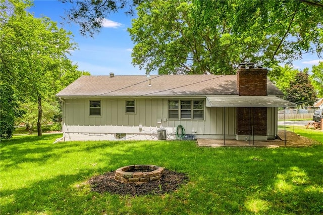 7201 E 130th Ter, Grandview, MO 64030 - back of property featuring board and batten siding, a chimney, a lawn, and a fire pit