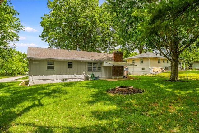 7201 E 130th Ter, Grandview, MO 64030 - back of house featuring an outdoor fire pit, a chimney, and board and batten siding