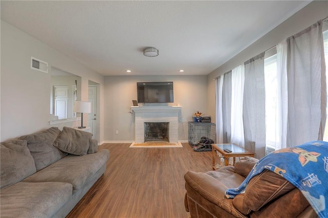 living area with visible vents, a fireplace, wood finished floors, baseboards, and recessed lighting