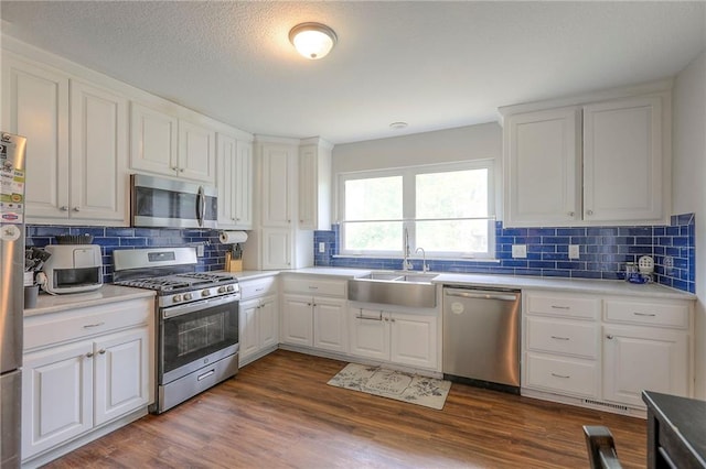 kitchen with a sink, appliances with stainless steel finishes, white cabinets, and backsplash