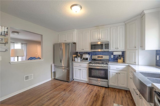 kitchen with appliances with stainless steel finishes, white cabinets, dark wood-style floors, and visible vents