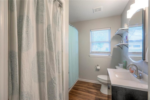 bathroom with vanity, toilet, baseboards, wood finished floors, and visible vents